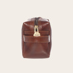 Neceser Lluta de cuero castaño de OLKI con cremallera dorada y asa lateral. Ideal para organizar artículos de aseo.