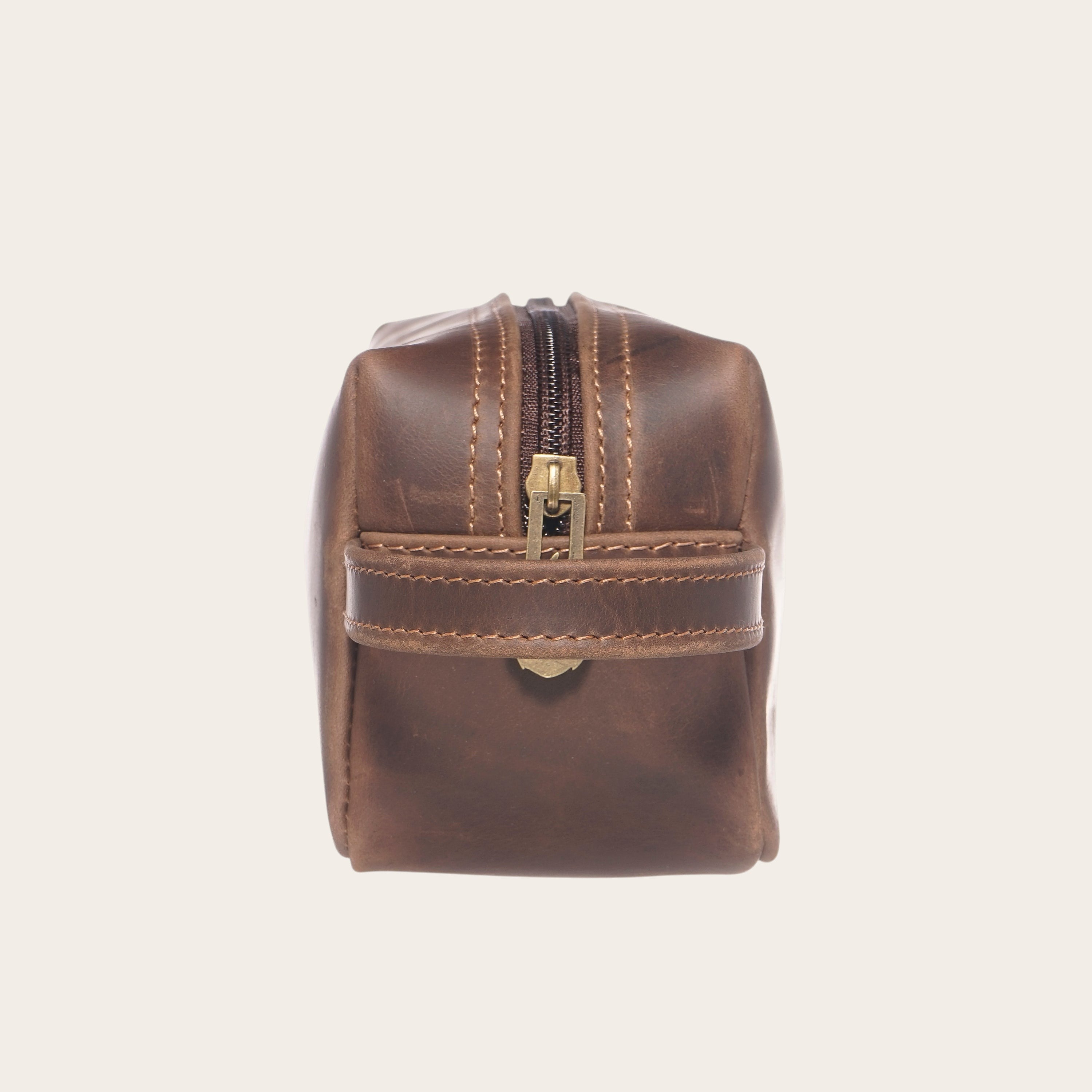 Neceser Lluta Chocolate de cuero marrón de OLKI con asa lateral y cierre metálico. Ideal para viajes.