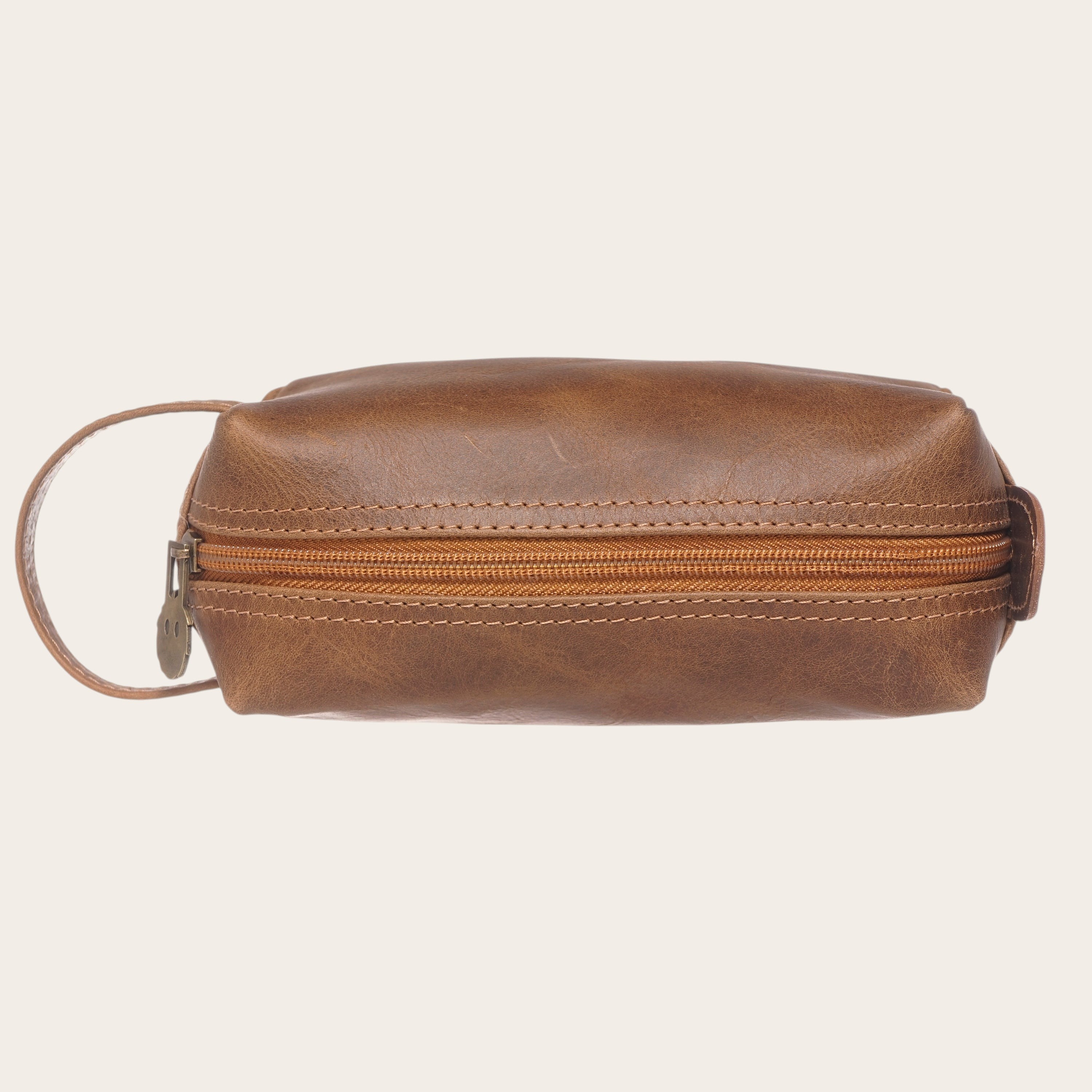 Neceser Lluta Habano de cuero curtido al natural en color marrón, con cremallera y asa lateral. Ideal para viajes.