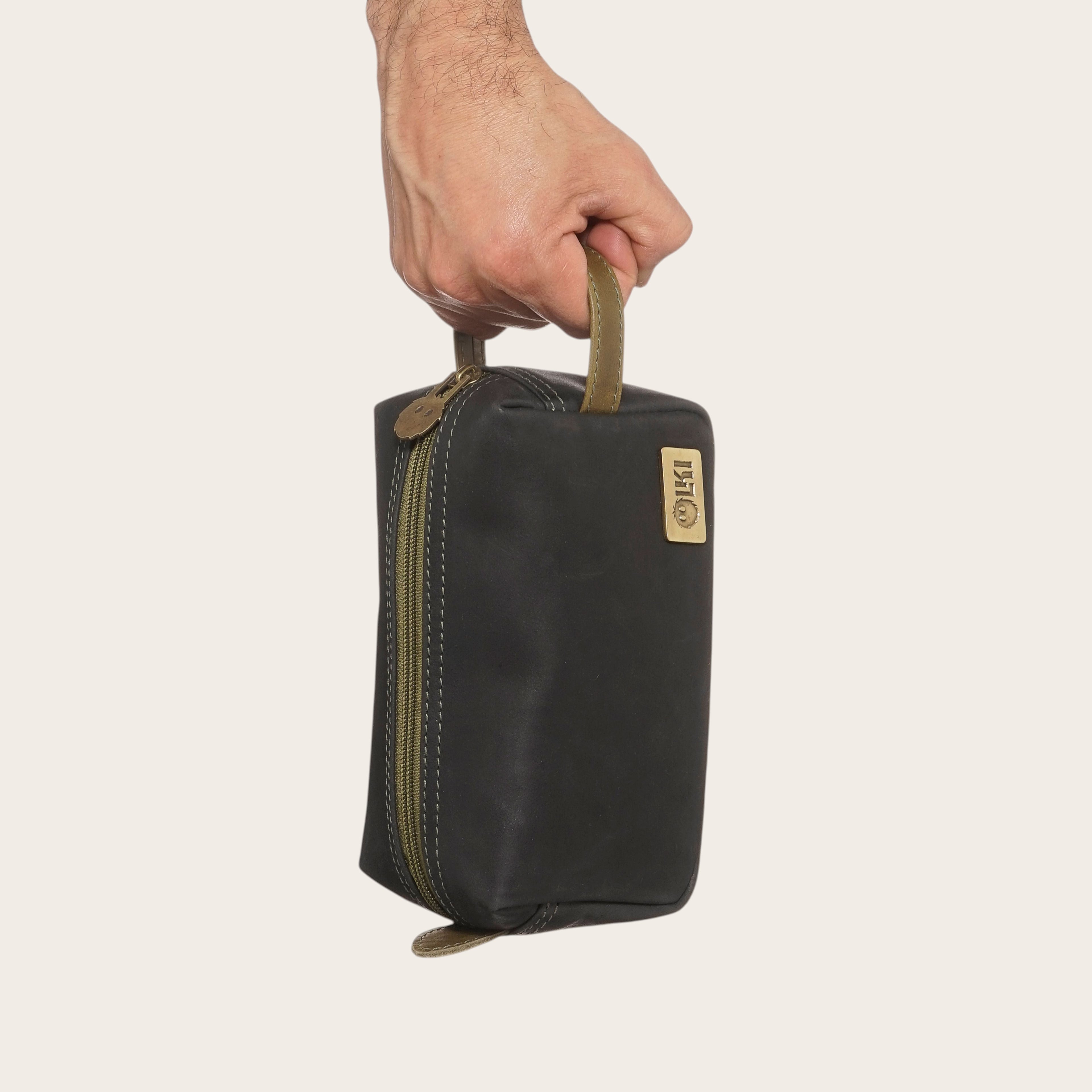 Neceser Lluta Negro-Verde de OLKI con asa lateral y cierre de cremallera, ideal para viaje.