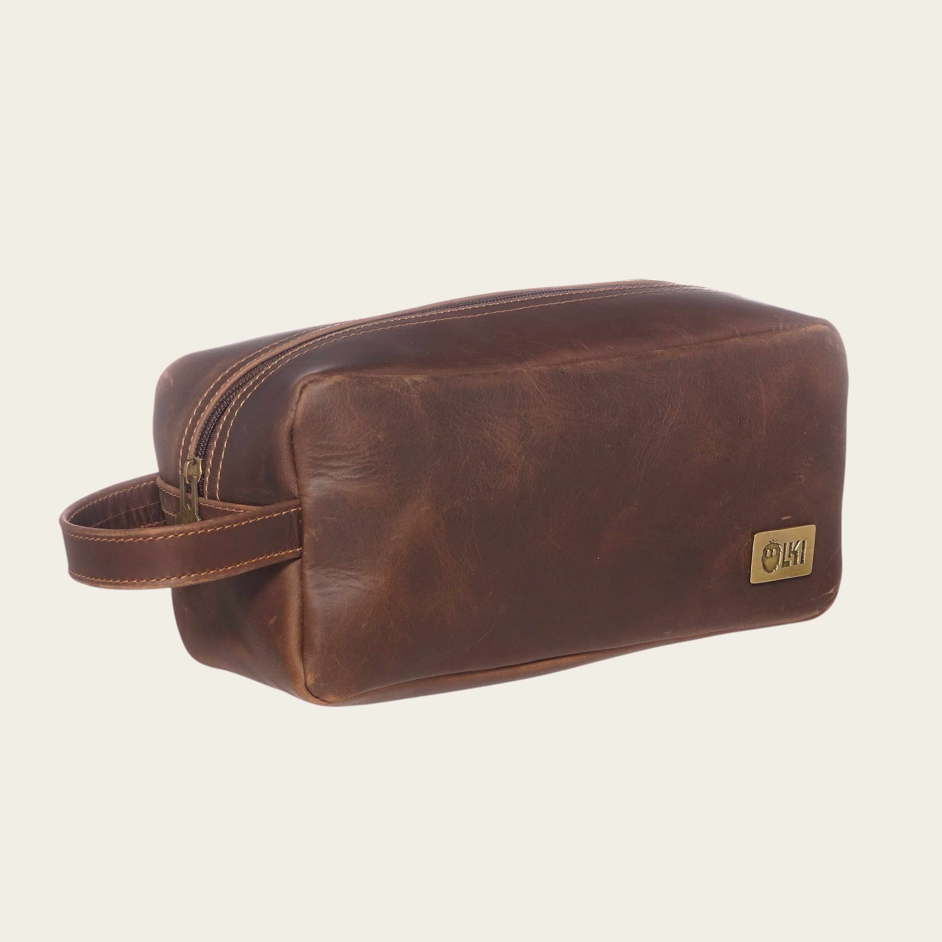 Neceser Loa Chocolate de cuero marrón de OLKI con asa lateral y cierre de cremallera, ideal para viajes.