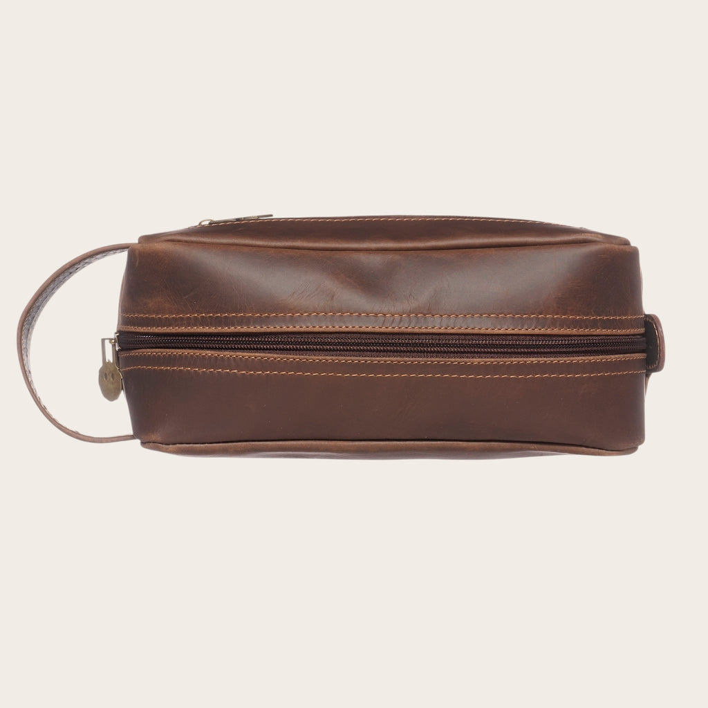 Neceser Loa Chocolate de cuero marrón de OLKI con asa lateral, ideal para viajes y organización.