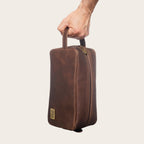 Neceser Loa Chocolate de cuero marrón de OLKI con asa lateral y cremallera dorada, ideal para viajes.