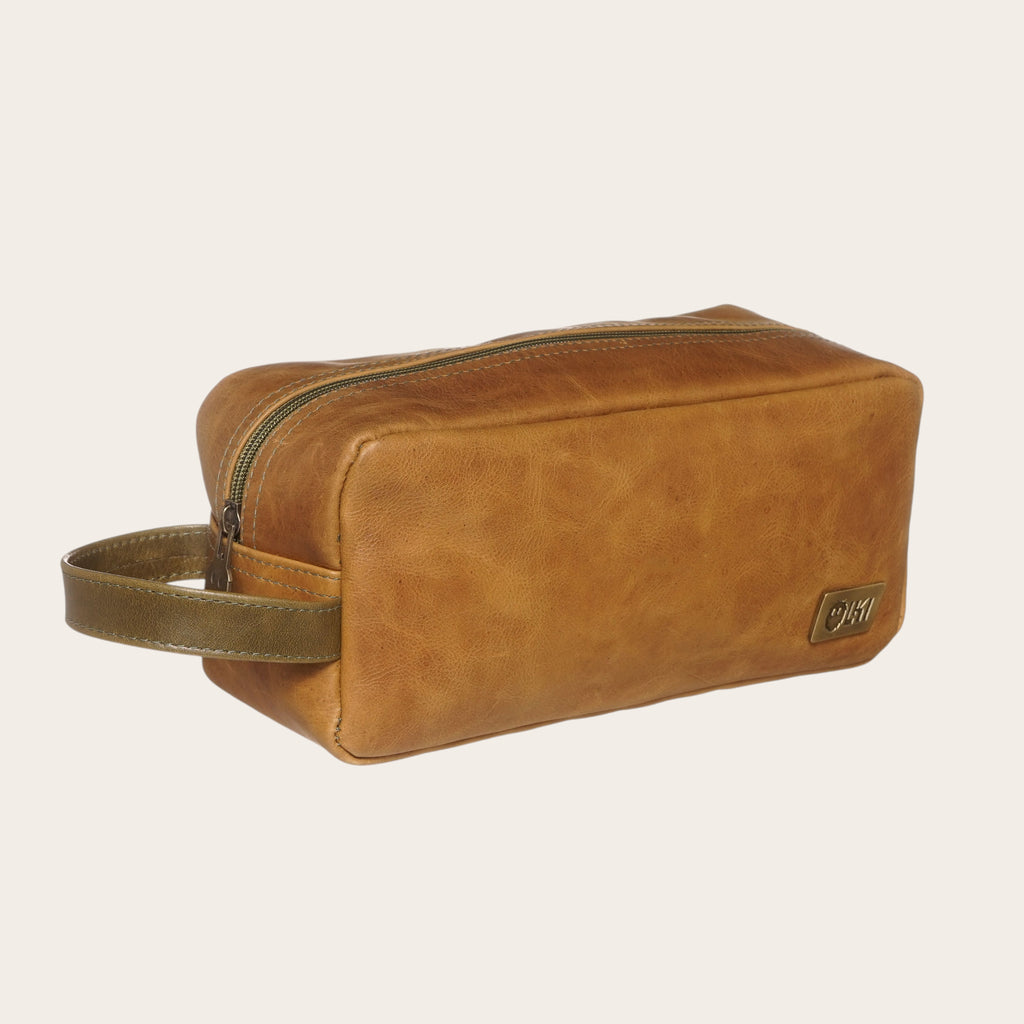 Neceser OLKI Loa de cuero color caramelo con cremallera y asa verde. Ideal para viajes y uso diario.