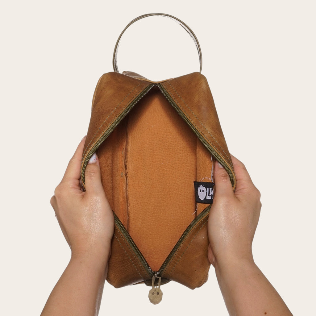 Neceser Loa de OLKI en cuero color caramelo con cremallera verde y asa lateral. Ideal para viajes y uso diario.