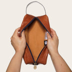 Neceser Loa de cuero tostado con detalles en azul marino, cremallera y tirador a juego. Ideal para viajes.