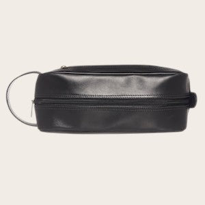 Neceser Loa Negro de cuero de OLKI con asa lateral y cierre de cremallera, ideal para organizar esenciales de viaje y aseo.