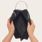Neceser Loa Negro de cuero de OLKI, con asa y cierre de cremallera, ideal para organizar esenciales de viaje o aseo.