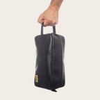 Neceser Loa Negro de cuero de OLKI con asa lateral y cierre de cremallera, ideal para organizar esenciales de viaje y aseo.