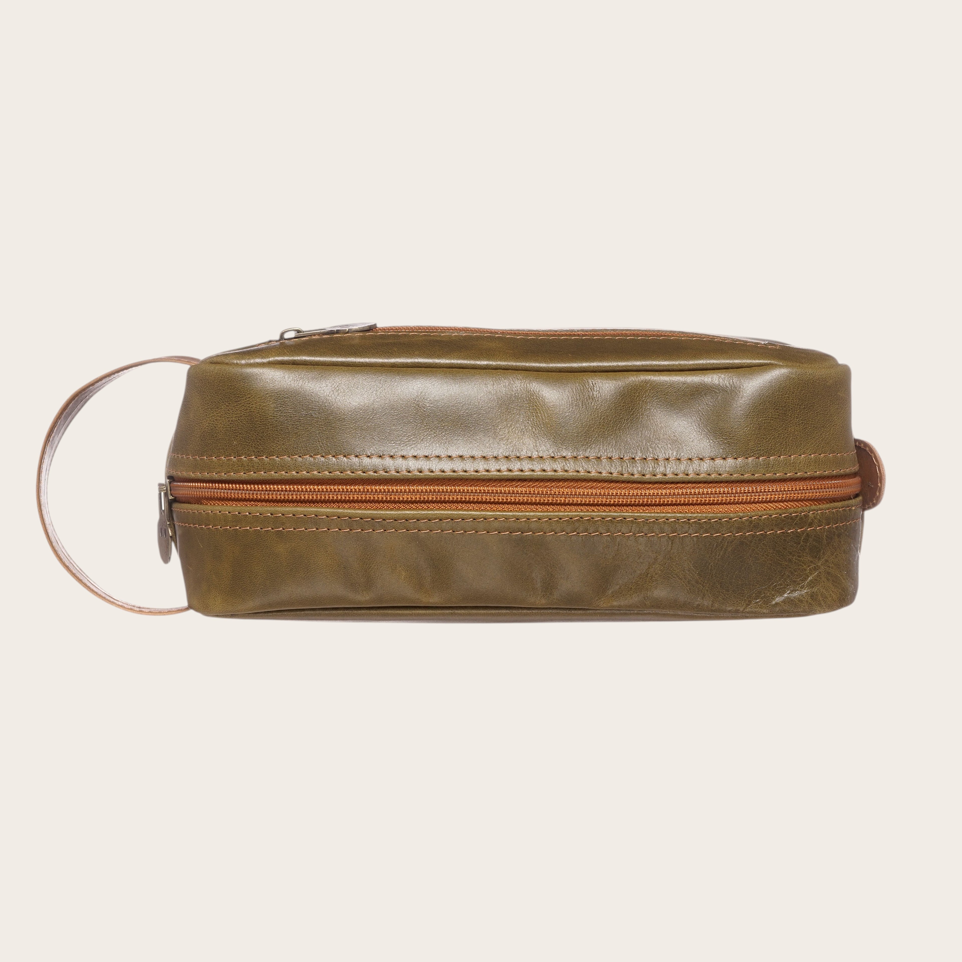 Neceser Loa de OLKI en cuero verde y caramelo, con cremallera y asa lateral. Ideal para viajes y uso diario.