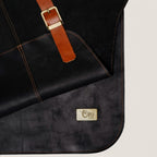 Pechera de cuero natural negro OLKI con costuras reforzadas, correa de ajuste color café y placa metálica de la marca