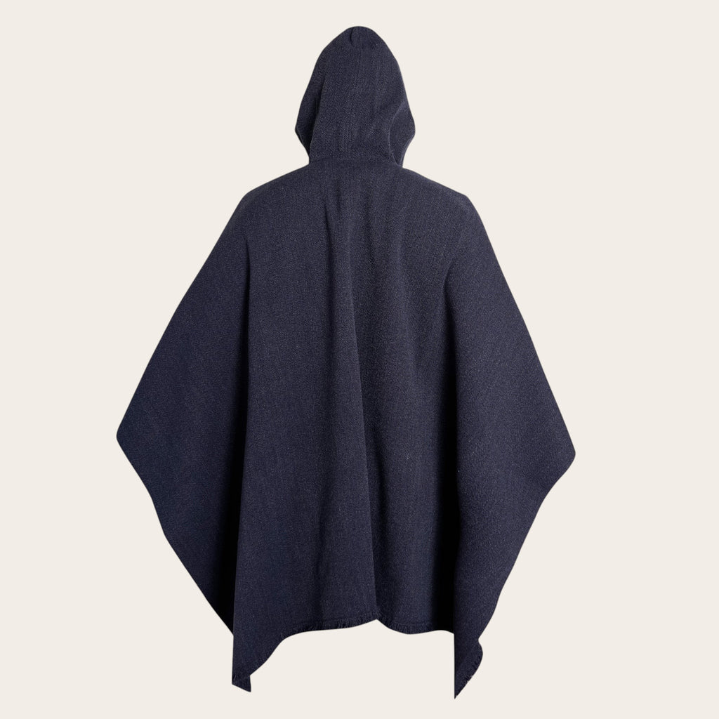 Poncho clásico azul marino de lana premium OLKI con capucha integrada, tejido en telar, textura firme y caída elegante.