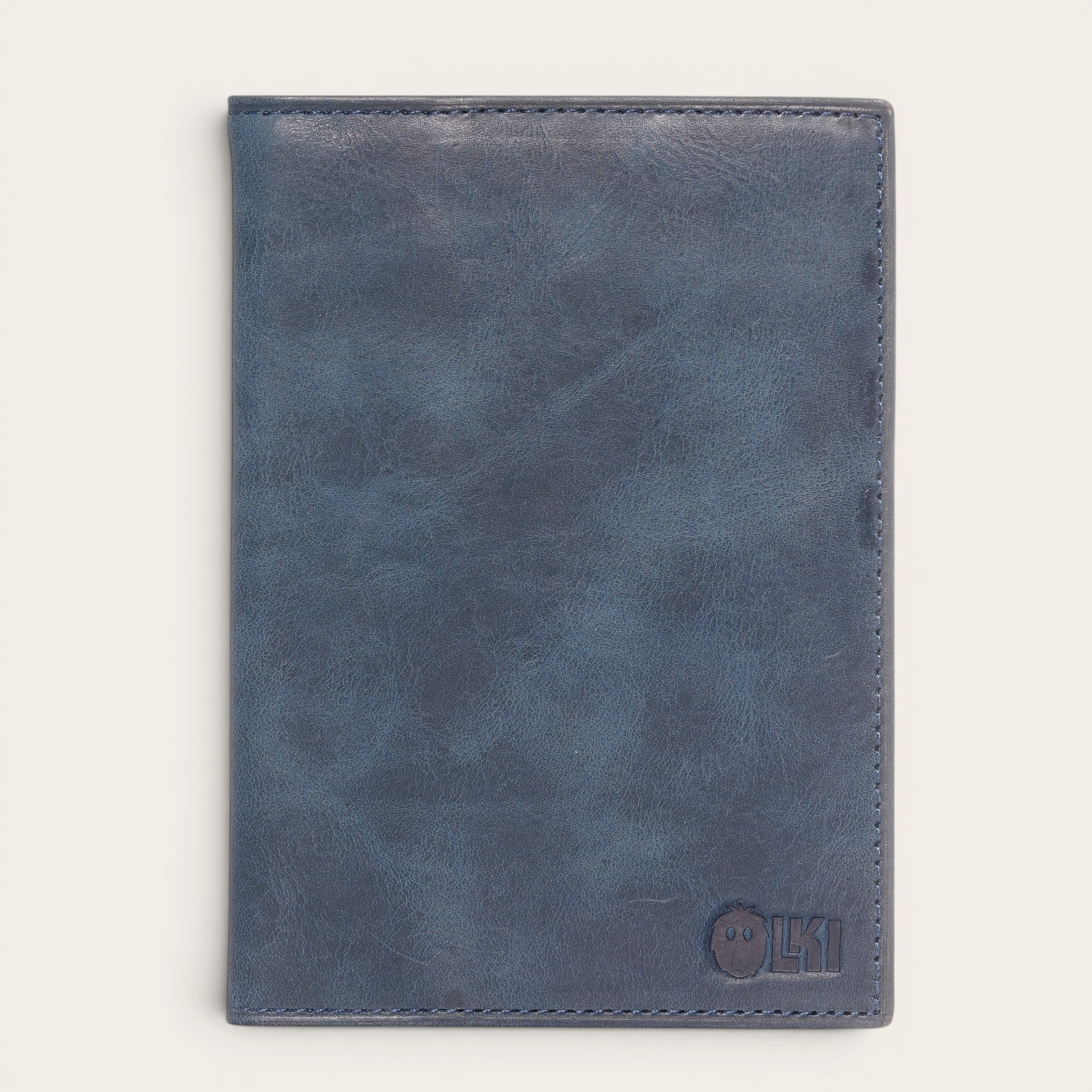 Porta pasaporte OLKI de cuero azul marino con 3 ranuras para tarjetas y separador interno. Dimensiones 10x14 cm.