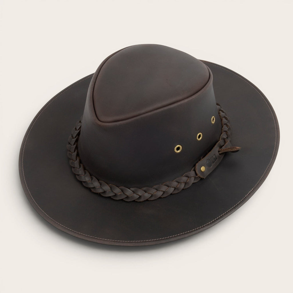 Sombrero de cuero marrón oscuro OLKI Pumalín con ala ancha, cinta trenzada y remaches metálicos. Estilo rústico y sofisticado.