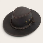 Sombrero de cuero marrón oscuro OLKI Pumalín con ala ancha, cinta trenzada y remaches metálicos. Estilo rústico y sofisticado.