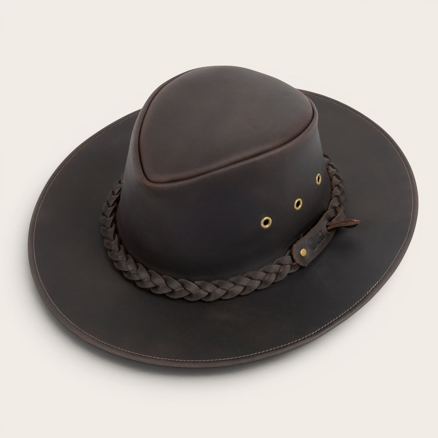 Sombrero de cuero marrón oscuro OLKI Pumalín con ala ancha, cinta trenzada y remaches metálicos. Estilo rústico y sofisticado.