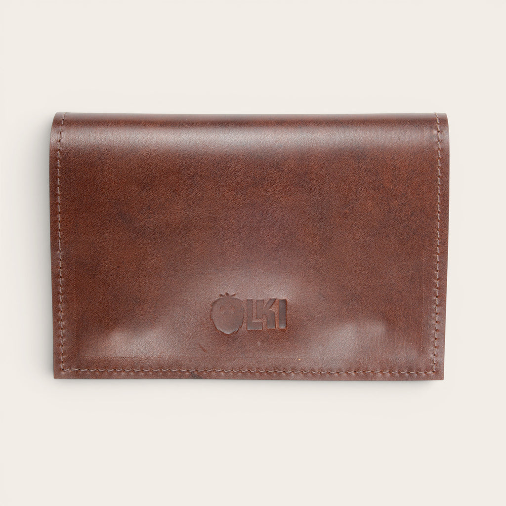 Tabaquera Maipo Castaño de cuero genuino marrón de OLKI con cierre a presión y logo grabado. Diseño compacto y elegante.
