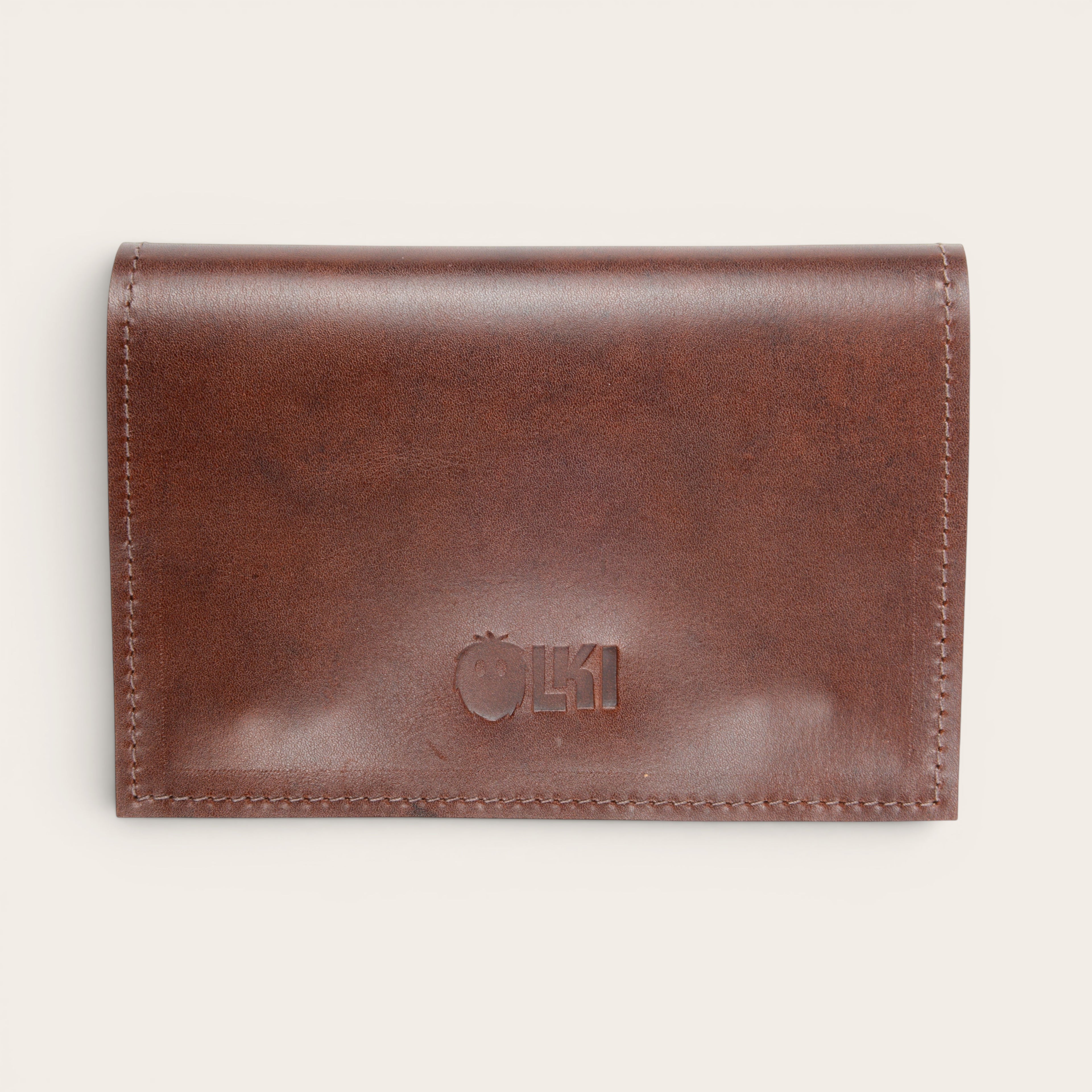 Tabaquera Maipo Castaño de cuero genuino marrón de OLKI con cierre a presión y logo grabado. Diseño compacto y elegante.
