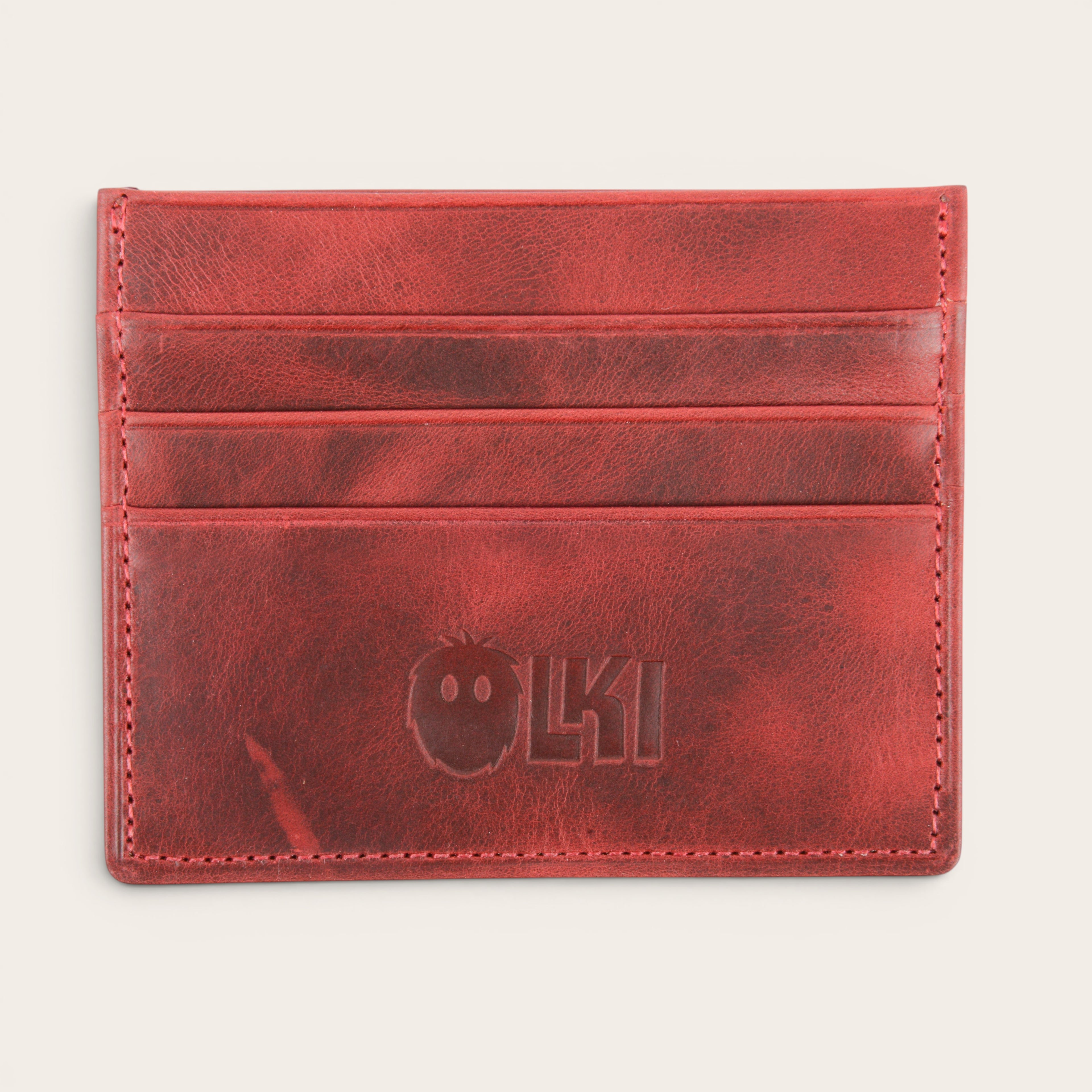 Tarjetero OLKI rojo de piel con múltiples ranuras para tarjetas y logo grabado. Diseño minimalista y funcional.