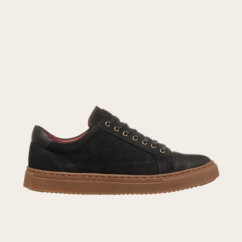 Zapatilla OLKI Aconcagua de cuero negro con detalles camel, suela marrón y ojales dorados.