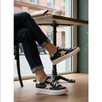 Zapatilla OLKI Tricahue negra con detalle de estrella dorada, cordones blancos y suela de plataforma blanca.