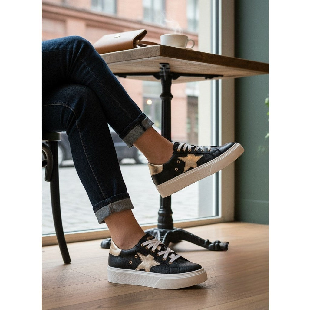 Zapatilla OLKI Tricahue negra con detalle de estrella dorada, cordones blancos y suela de plataforma blanca.