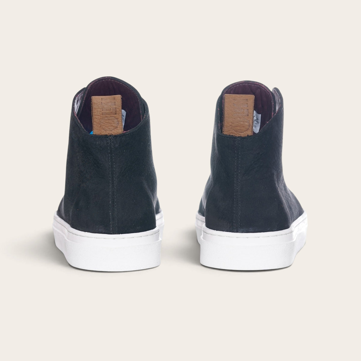 Vista trasera de zapatillas altas OLKI Manquehue en cuero negro con suela blanca y etiqueta de cuero en el talón